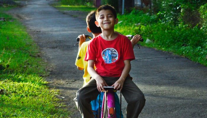 boy riding on back of bicycle